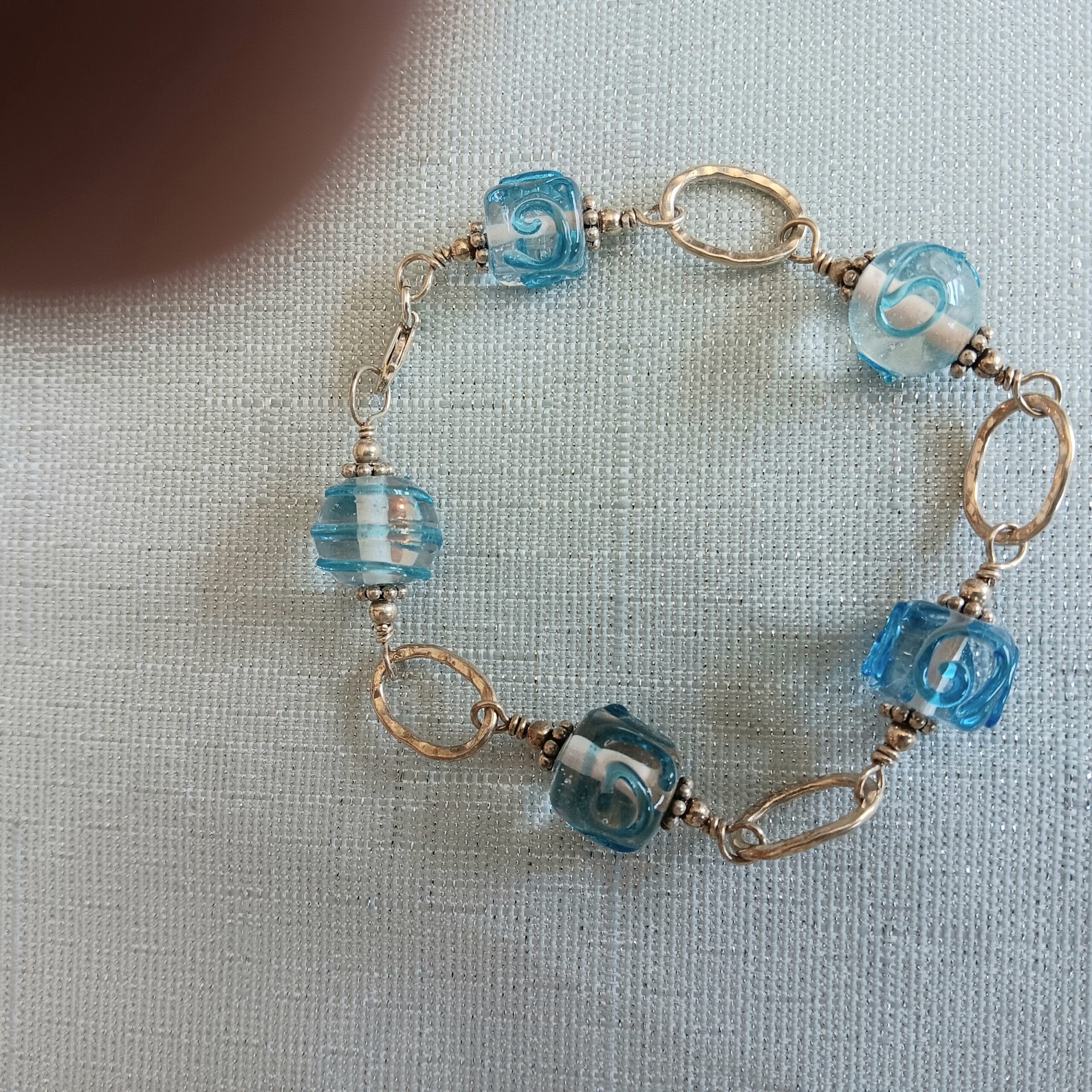 Bracelet of sterling ovals and lamp work teal beads
